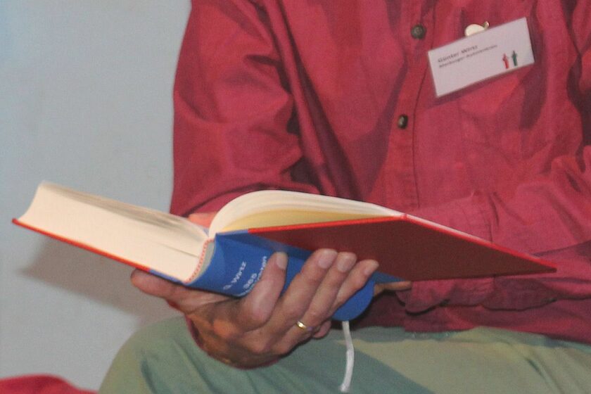 Ein Mann hält ein aufgeschlagenes Buch in den Händen