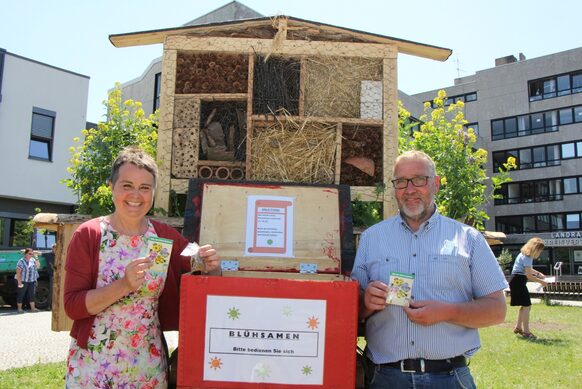 Landrätin Kirsten Fründt und Kreislandwirt Frank Staubitz zeigen die rote Box an dem Wagen, in dem es die Blühsamen zum Mitnehmen gibt.