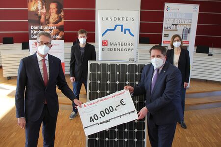 Vier Vertreter*innen von Landkreis und Sparkasse mit einem übergroßen Scheck