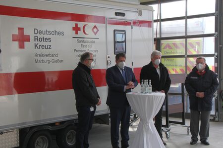 Vier Menschen vor einem Fahrzeug vom Deutschen Roten Kreuz