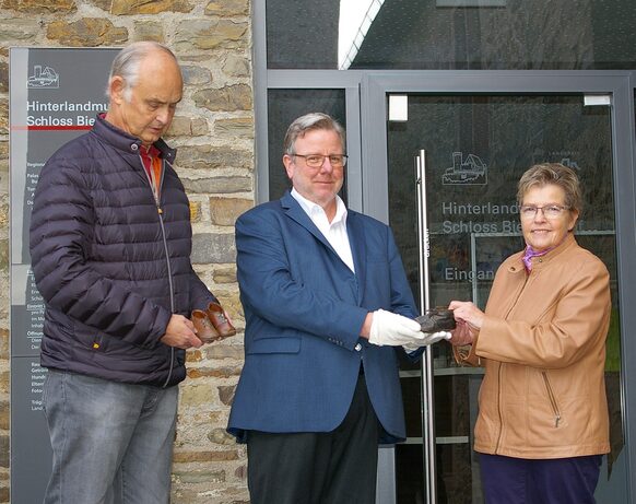 Ute Davidis überreicht gemeinsam mit ihrem Ehemann Jürgen (l.) dem Leiter des Hinterlandmuseums, Dr. Andreas W. Vetter, die zwei Paar Lauflernschuhe.