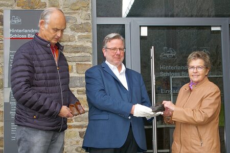 Ute Davidis überreicht gemeinsam mit ihrem Ehemann Jürgen (l.) dem Leiter des Hinterlandmuseums, Dr. Andreas W. Vetter, die zwei Paar Lauflernschuhe.