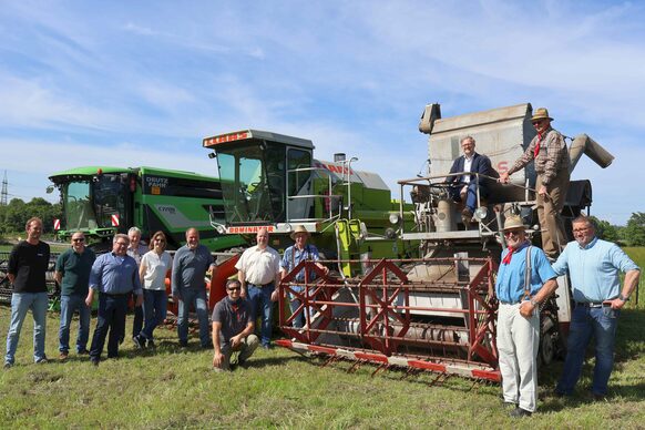 Landrat Jens Womelsdorf sowie Vertreterinnen und Vertreter der Landwirtschaft und des Kreises vor Mähdreschern aus verschiedenen Zeiten.