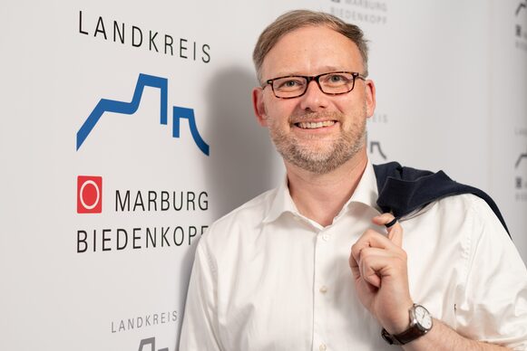 Landrat Jens Womelsdorf vor einem Landkreis-Logo