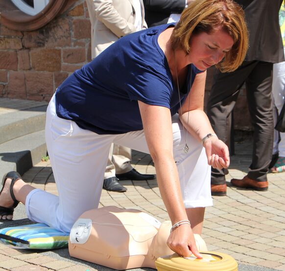 Fronhausens Bürgermeisterin Claudia Schnabel demonstriert an einem Dummy den Einsatz eines AED-Gerätes.