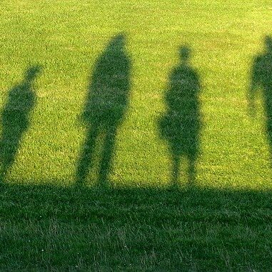 Schatten von vier Menschen auf Gras