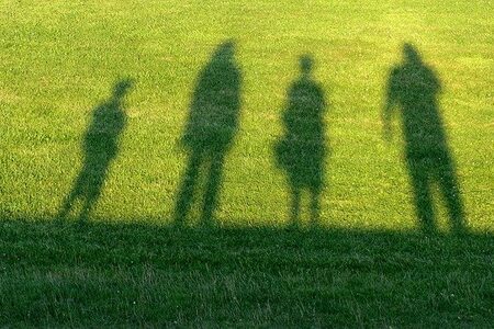 Schatten von vier Menschen auf Gras